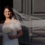 sposa con il velo davanti al portone di una cattedrale storica italiana durante il giorno del matrimonio